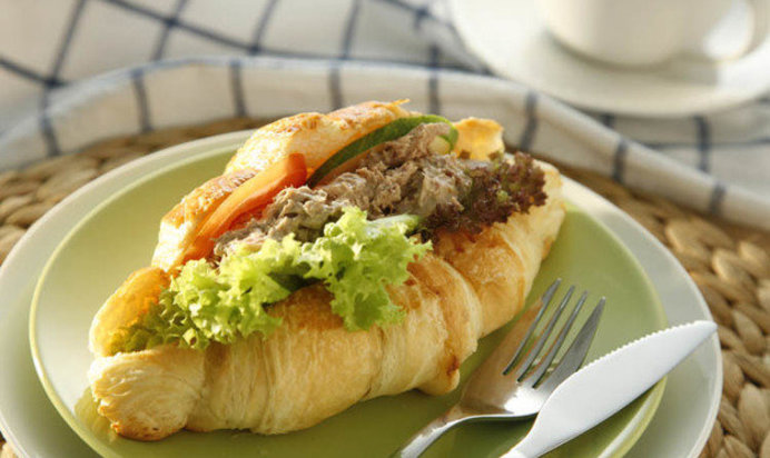 Круассан с тунцом, листьями салата и помидором