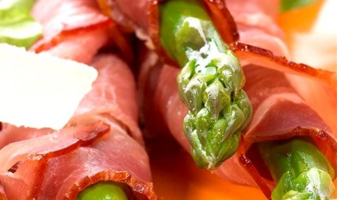 Спаржа, завернутая в ветчину серрано, с листьями салата, миндалем и виноградом